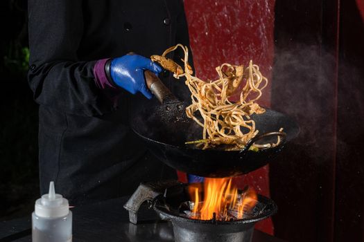 Flying noodles for wok box with meat, soy sauce fried in a wok pan, street food.