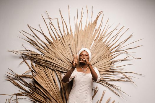 Portrait of black business lady on the dry leaves background. African model is posing in studio