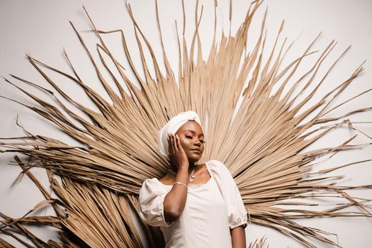 Portrait of black business lady on the dry leaves background. African model is posing in studio