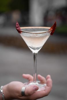 Cocktail in glass with chili on gray background. Devil alcohol drink