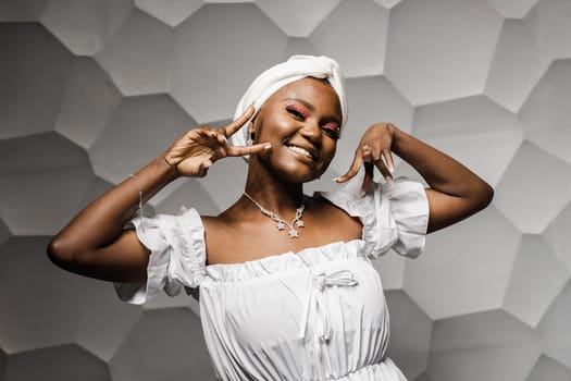 Black muslim woman holding up 2 fingers have party. African girl is celebrating her birthday and having fun.