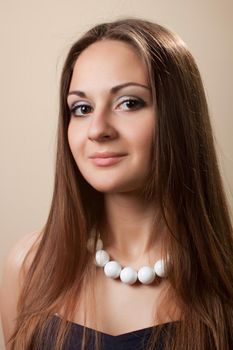 Portrait of a beautiful young girl with long dark brown hair and large beads around her neck.