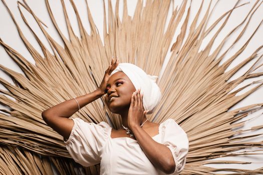 Portrait of black business lady on the dry leaves background. African model is posing in studio