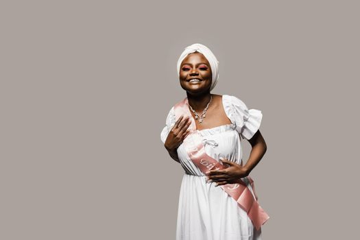 Happy muslim woman with birthday ribbon on gray background. Black african woman is celebrating her birthday