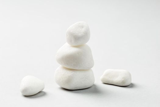 Stacked White zen rocks balance on the grey background. Balancing pebble stones 