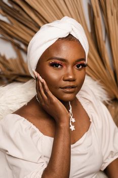 Portrait of black business lady on the dry leaves background. African model is posing in studio