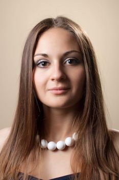 Portrait of a beautiful young girl with long dark brown hair and large beads around her neck.