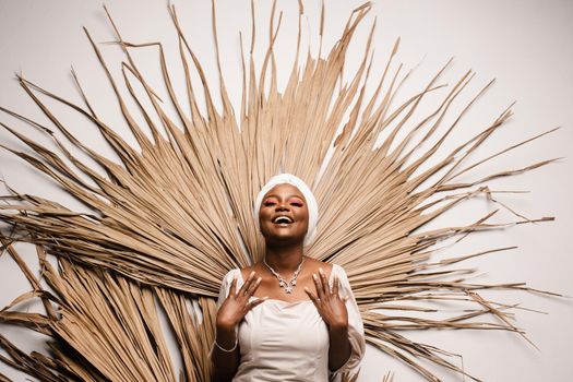 Portrait of black business lady on the dry leaves background. African model is posing in studio