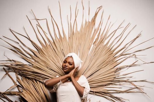 Portrait of black business lady on the dry leaves background. African model is posing in studio