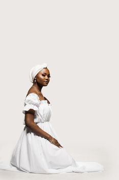 Black muslim woman is praying solat. Attractive woman in white dress sit and pray on whita background