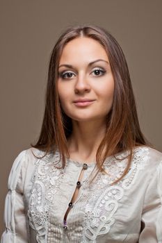 Portrait of fashionable young woman weared in light grey evening dress on biege background