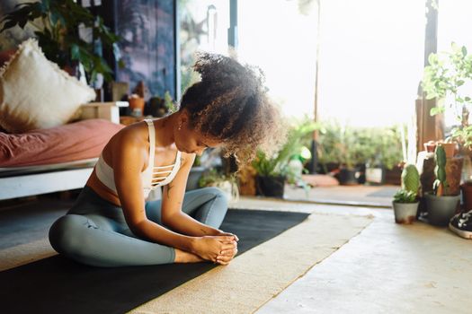 Shot of a young woman practising yoga in her living room - Stock Photo