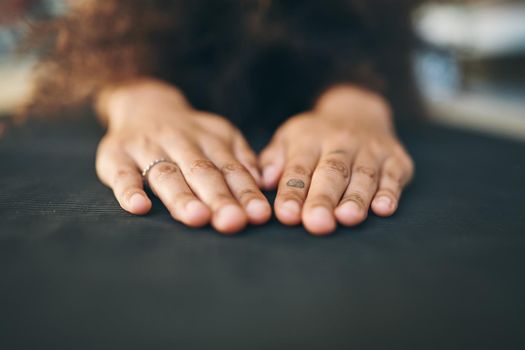 Closeup shot of an unrecognizable woman meditating on her yoga mat - Stock Photo