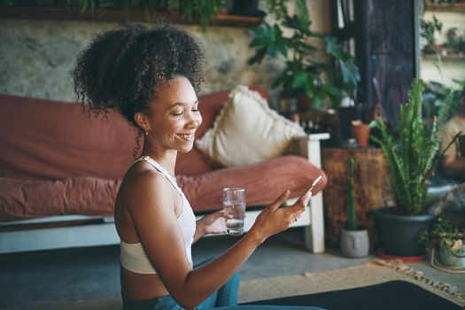 Shot of a young beautiful girl in her sportswear smiling at her cellphone