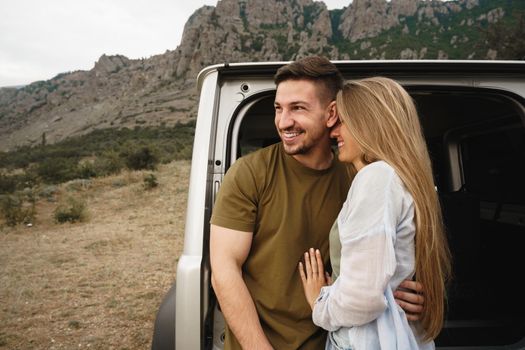 Young happy couple on a road trip sitting in car trunk outdoor