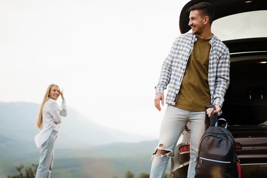 Young couple on road trip relaxing and enjoying the view of mountains