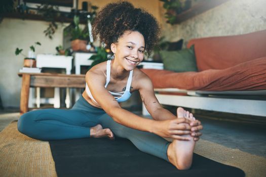 Shot of a sporty young woman stretching her legs while looking at the camera - Stock Photo