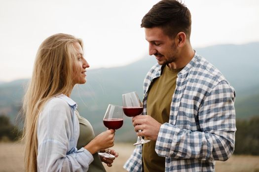 Smiling couple toasting wine glasses outdoors in mountains, close up portrait