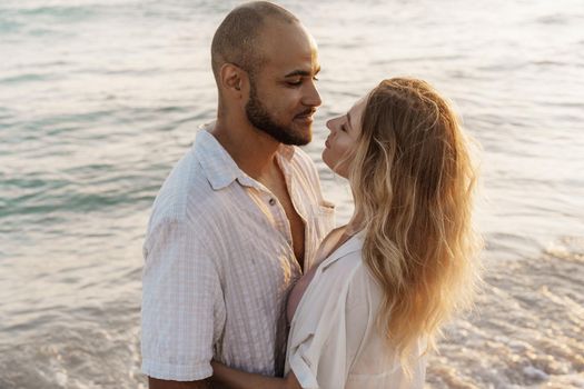 Beautiful young couple hugging on the beach by the water, close up