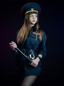 woman in a Russian police uniform with a baton. English translation Police