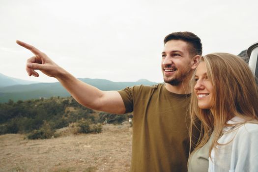 Young couple on road trip relaxing and enjoying the view of mountains