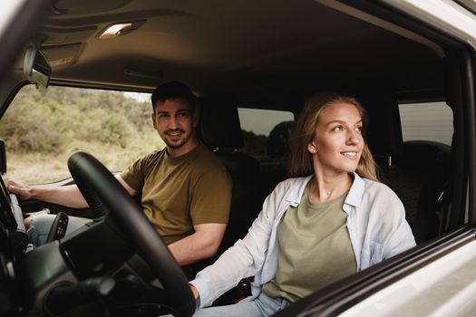 Beautiful young smiling couple sitting on front passenger seats and driving a car