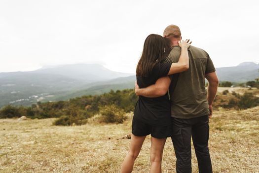 Happy couple in love hugging smiling and having fun in the mountains on foggy day