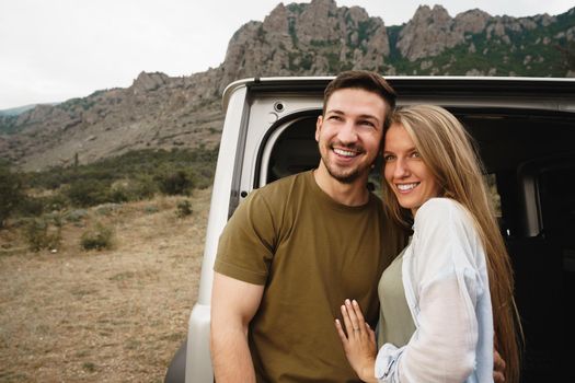 Young happy couple on a road trip sitting in car trunk outdoor