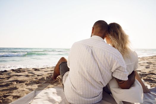 Beautiful couple sitting at the beach watching the sunset, close up