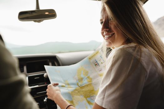 Young loving couple on a road trip using map inside a car, close up