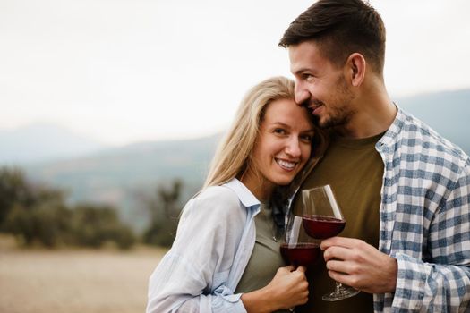 Smiling couple toasting wine glasses outdoors in mountains, close up portrait