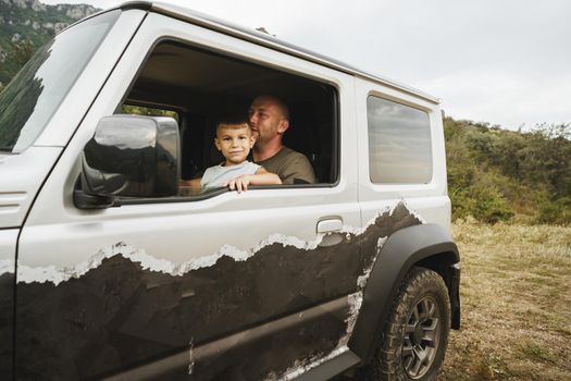 Father teaches little son to drive on road trip, close up