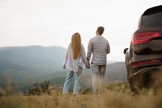 Young couple on road trip relaxing and enjoying the view of mountains