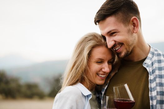 Smiling couple toasting wine glasses outdoors in mountains, close up portrait