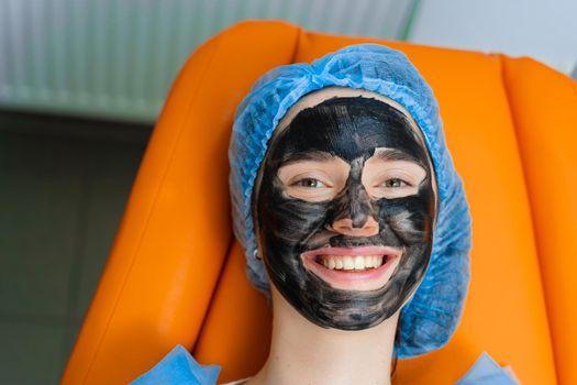 Black mask on girl face for carbon peeling. Dermatology and cosmetology. Using surgical laser