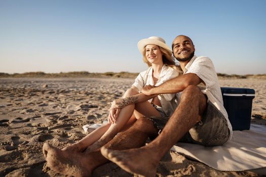 Beautiful couple sitting at the beach watching the sunset, close up