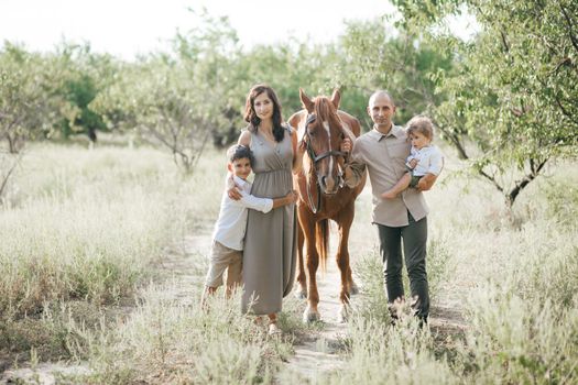 Happy young family with two children on wheat summer field. Adventure, travel, tourism, hike and people concept - happy family walking