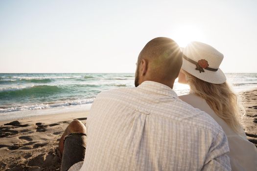 Beautiful couple sitting at the beach watching the sunset, close up