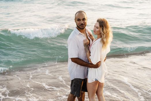 Beautiful young couple hugging on the beach by the water, close up