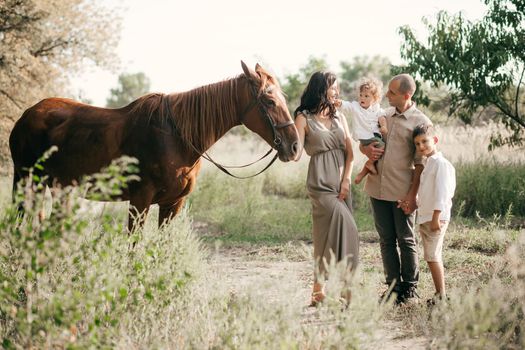 Happy young family with two children on wheat summer field. Adventure, travel, tourism, hike and people concept - happy family walking