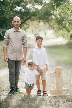 Happy young man with children on wheat summer field. Happy fatherhood. Adventure, travel, tourism, hike and people concept - happy family walking