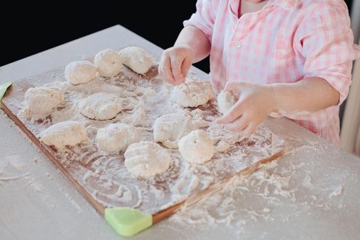 Happy wife smiling and preparing breakfast together with child for husband. Beautiful mother with cute daughter cooking in pajamas in morning. Little lovely kid helping parent with dough at kitchen.