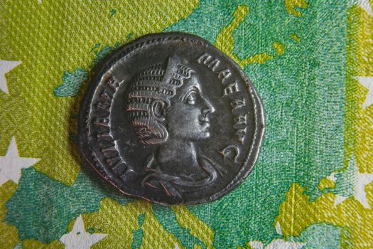 old roman coin lies on euro banknote close up