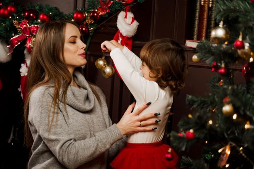 Mom and daughter decorate the christmas tree before the new year. Family traditions. Preparing for new year celebration