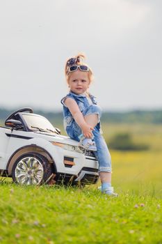 girl in sunglasses stands near the car in nature