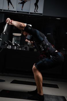 Man in EMS suit and medical mask in gym. Protection from coronavirus covid-19. Sport training in electrical muscle stimulation suit at quarantine period