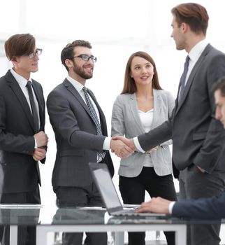 Business partners handshaking over business objects on workplace.