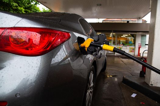 The car is refueling at the gas station. Refueling automobile with gasoline or diesel with a fuel dispenser.