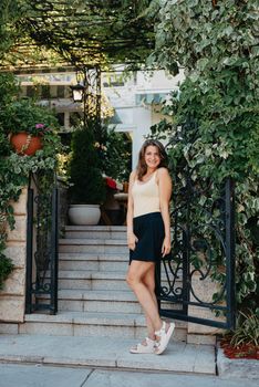 Girl tourist walking through ancient narrow street on a beautiful summer day in MEDITERRANEAN MEDIEVAL CITY , OLD TOWN bUDVA, MONTENEGRO. Young beautiful cheerful woman walking on old street at tropical town. Pretty girl looking at you and smiling