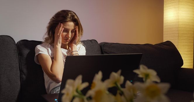 Young woman working on laptop alone in dark living late at night